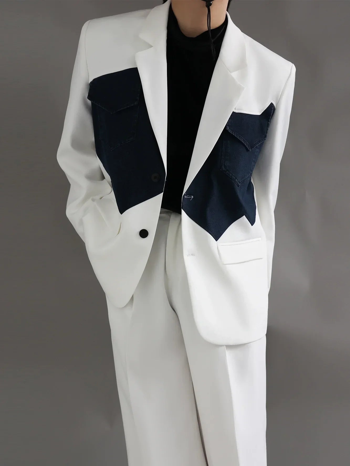 White suit with black shirt and navy denim pocket accents, fashion-forward outfit on model
