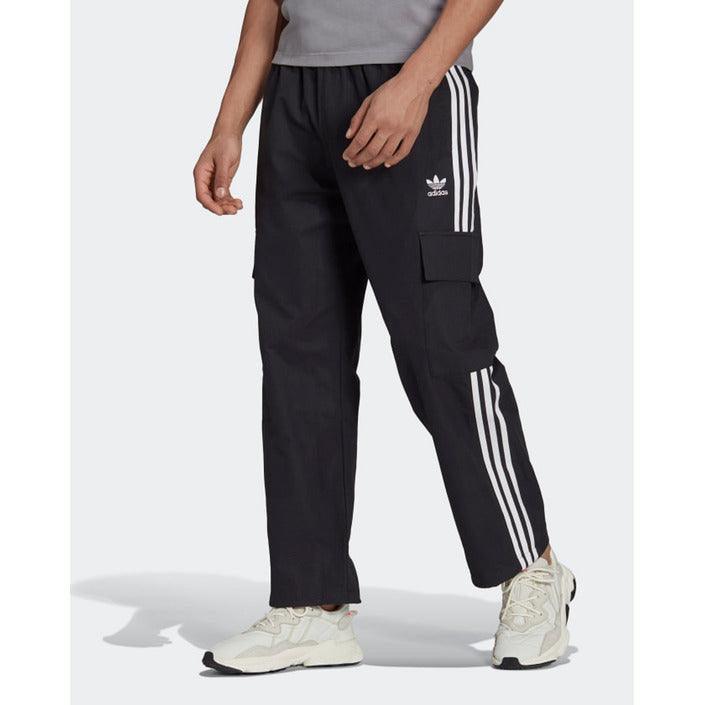 Black Adidas cargo trousers with white stripes and logo, worn with white sneakers
