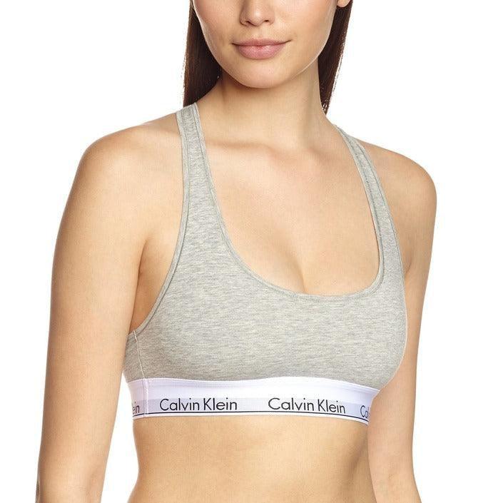 Woman wearing Calvin Klein grey sports bra, branded underwear collection, studio setting
