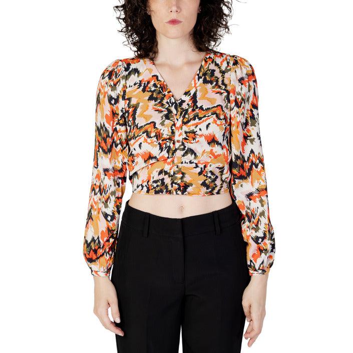 Woman wearing a vibrant patterned long sleeve crop top and black pants, fashion apparel