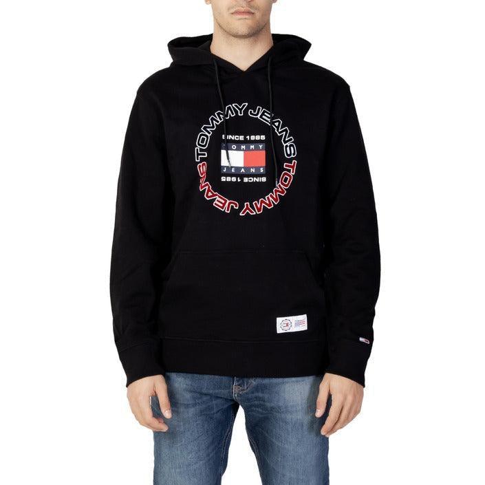 Man wearing black Tommy Jeans hoodie with logo and blue jeans, stylish men's streetwear