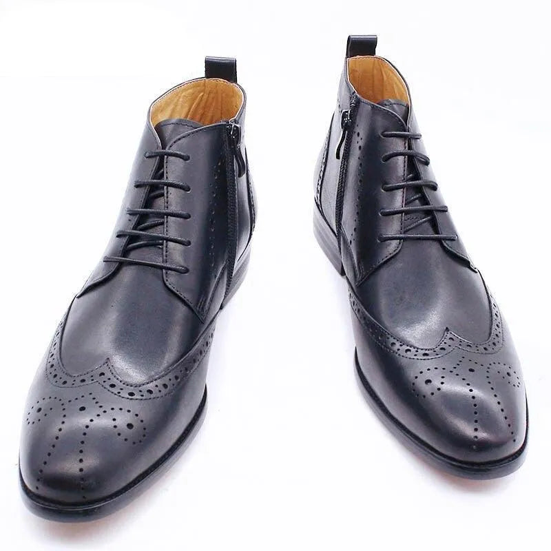 Black formal leather ankle boots with brogue detailing on white background
