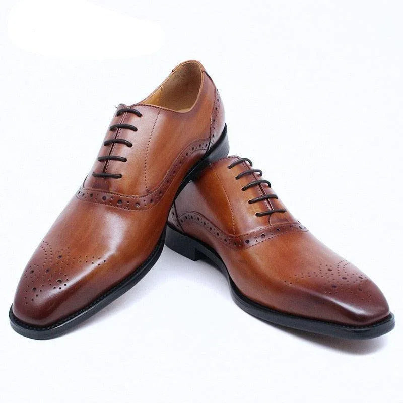 Brown leather lace-up men’s dress shoes with brogue detailing on white background