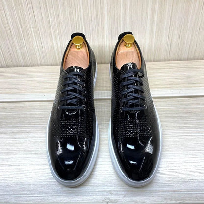 Glossy black leather dress sneakers with white soles on a light wooden surface