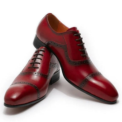 Red pointed toe men's dress shoes with black brogue detailing on a white background