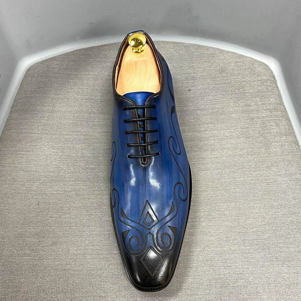 Blue leather men's dress shoe with black patterns and laces on a gray fabric surface