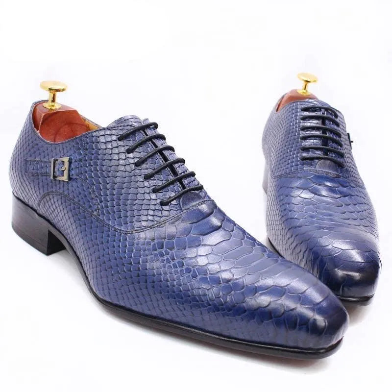 Blue men’s dress shoes with lizard skin texture, lace-up, and buckle detail on white background