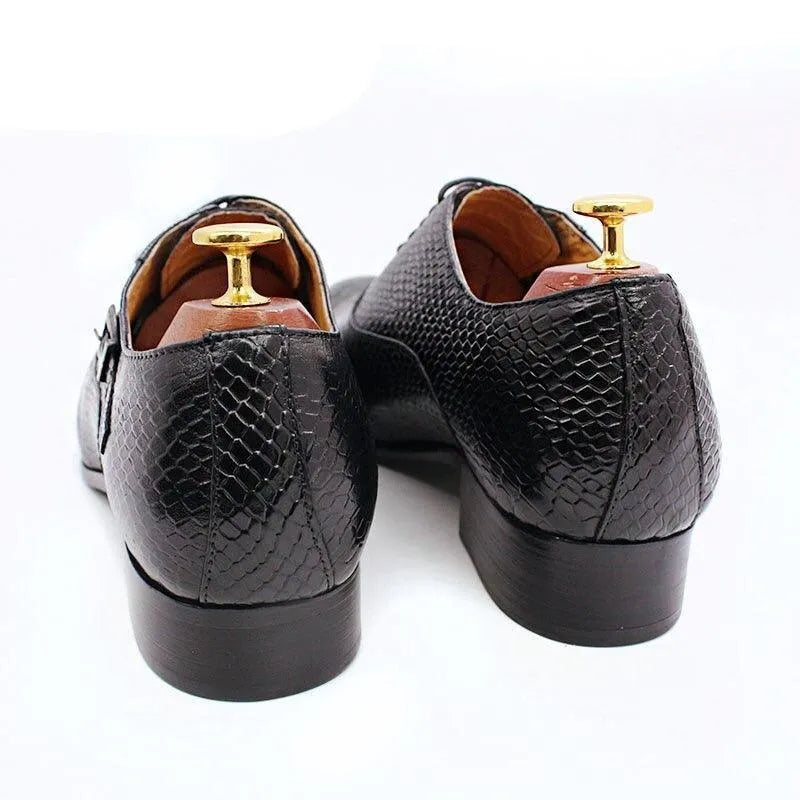 Black snakeskin pattern leather men’s dress shoes with shoe trees on white background