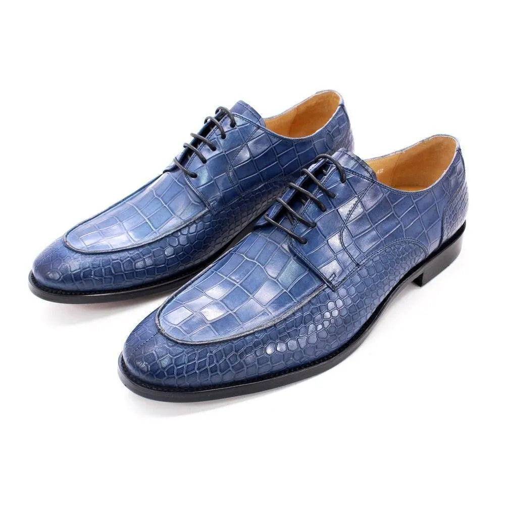 Blue crocodile pattern leather men's dress shoes with black soles on white background