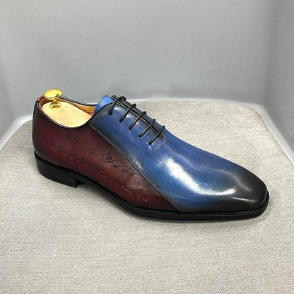 Men's color block dress shoe with blue, burgundy, and black leather, lace-up, on gray fabric