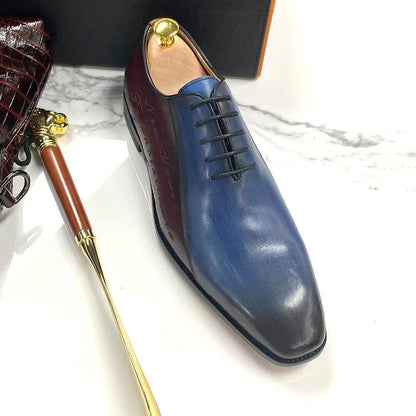 Color block blue and black men's dress shoe with laces on marble surface