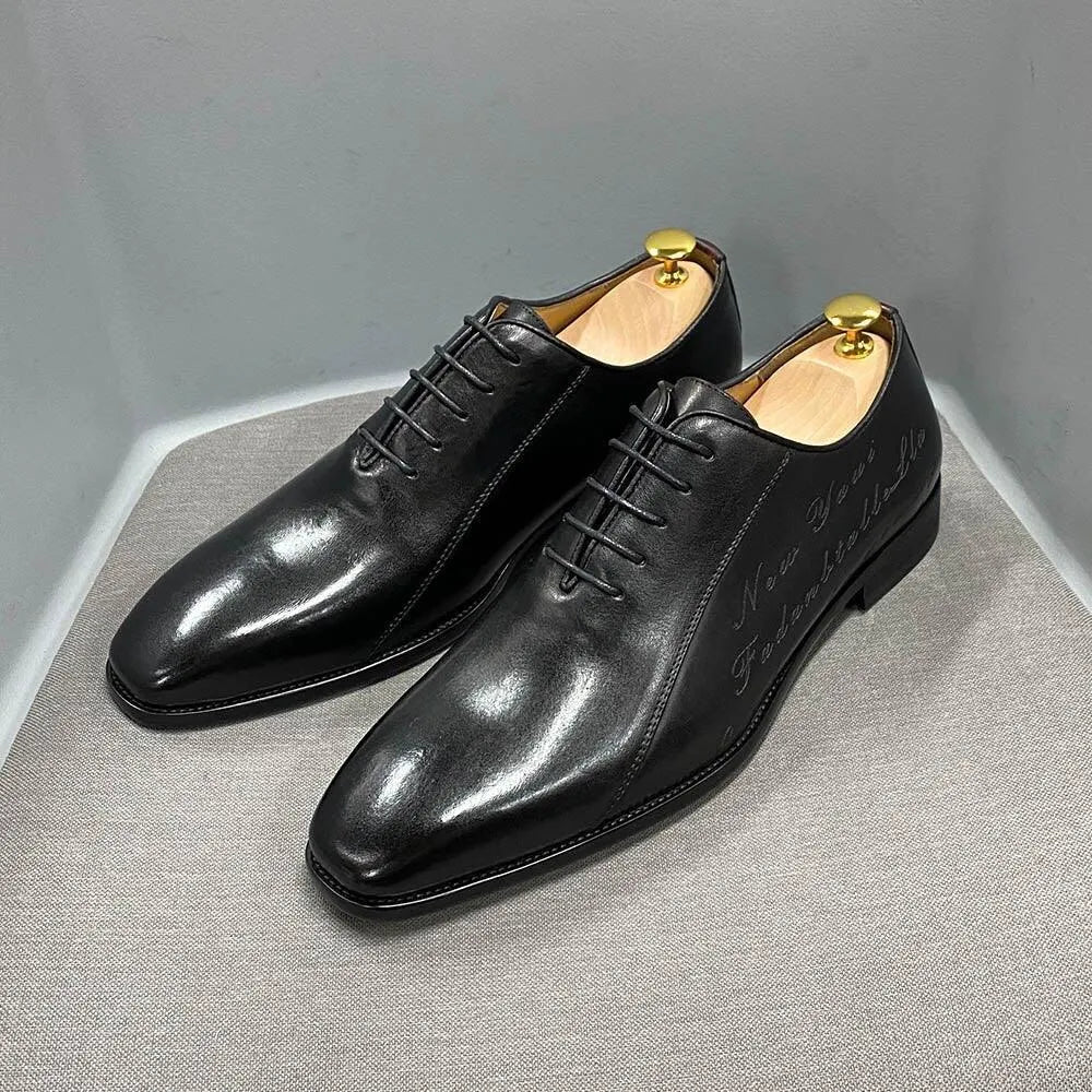 Black leather men's dress shoes with laces and shoe trees on a gray surface