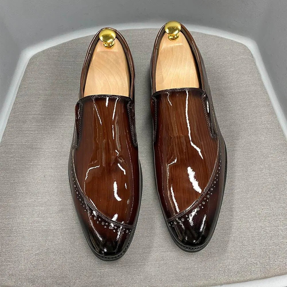 Glossy brown men's dress slip-on shoes with brogue detail displayed on a gray surface