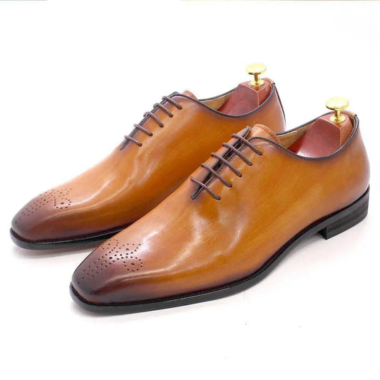 Brown leather men’s oxford dress shoes with laces and perforated toe detail on white background.