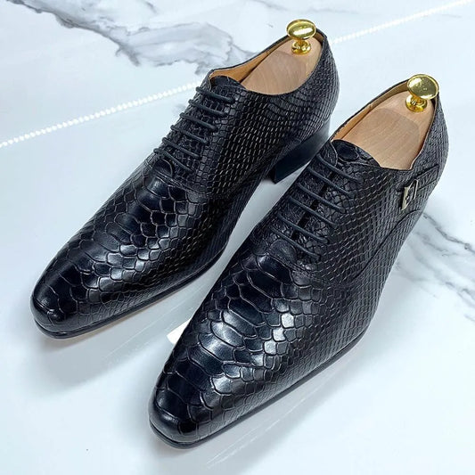 Black snakeskin pattern men's dress shoes on marble surface