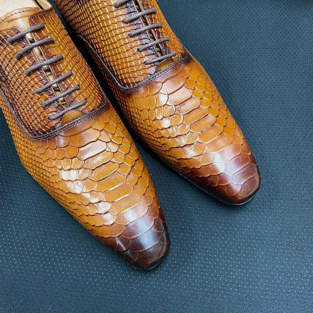 Brown men's dress shoes with snake skin texture on a dark textured surface