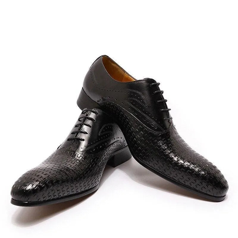 Black pointed toe dress shoes with textured leather and lace-up design on white background