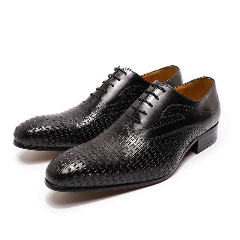 Black leather dress shoes with pointed toes and textured woven pattern on white background