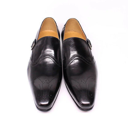 Black pointed toe men's dress shoes with brogue detail and buckle on white background