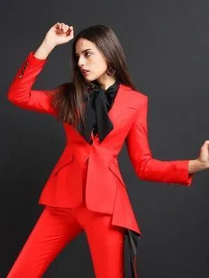 Woman in red flared pant suit with black blouse, posing against black background