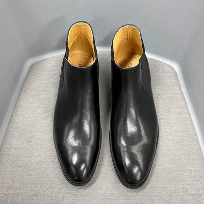 Black leather ankle dress boots with tan lining on a gray surface