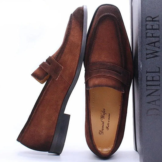 Brown suede men's dress loafers with a low heel, displayed beside a Daniel Wafer shoe box